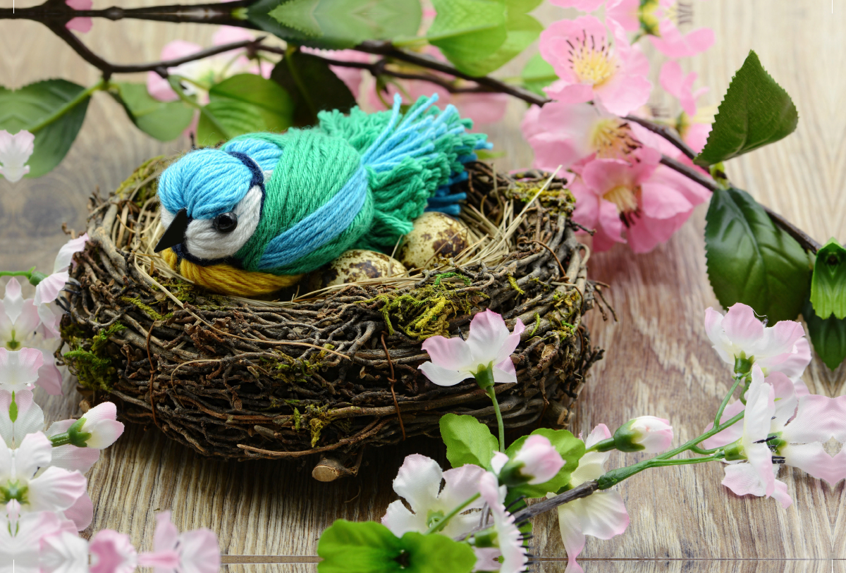 Gebastelte Blaumeise aus Wolle in einem Nest.