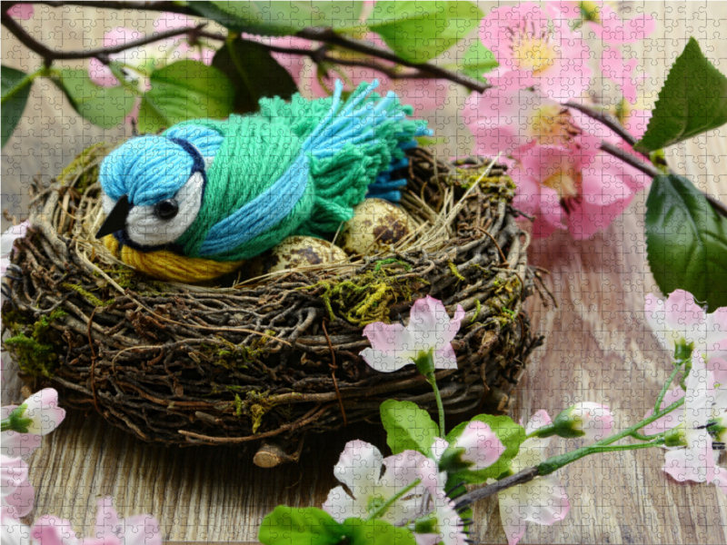 Gebastelte Blaumeise aus Wolle in einem Nest.