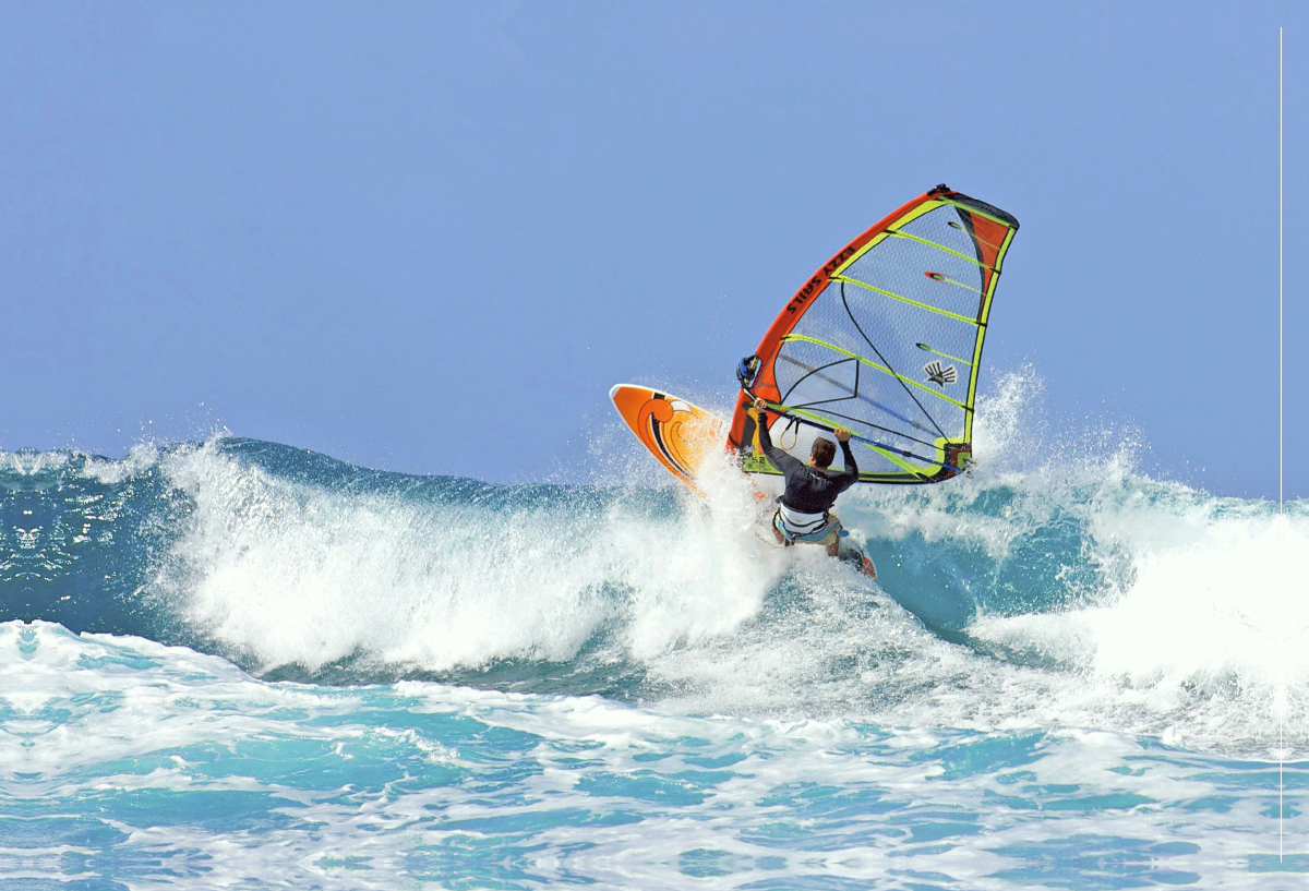 Beherzter Windsurfer gleitet rasant durch die Brandung.