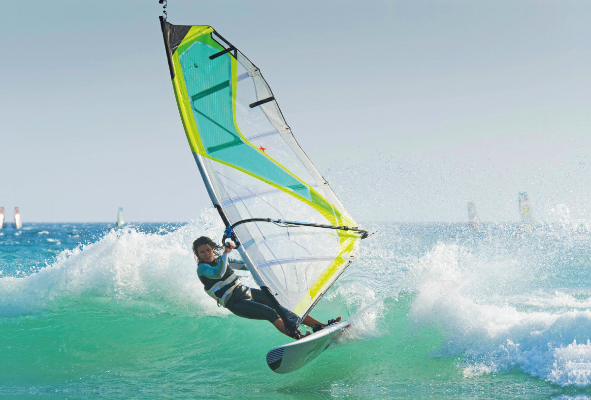 Sportliche junge Windsurferin in der schäumenden Welle.