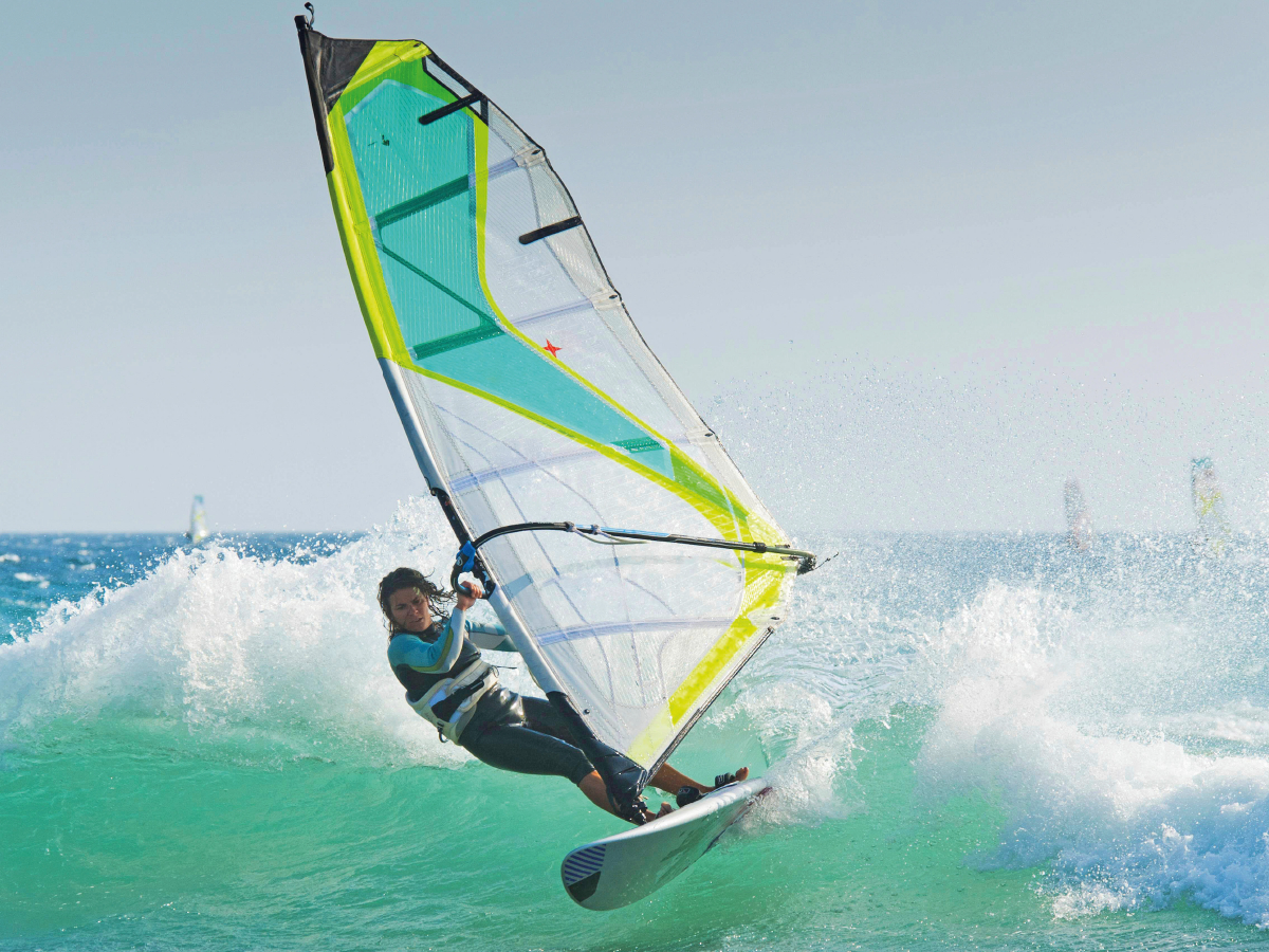 Sportliche junge Windsurferin in der schäumenden Welle.