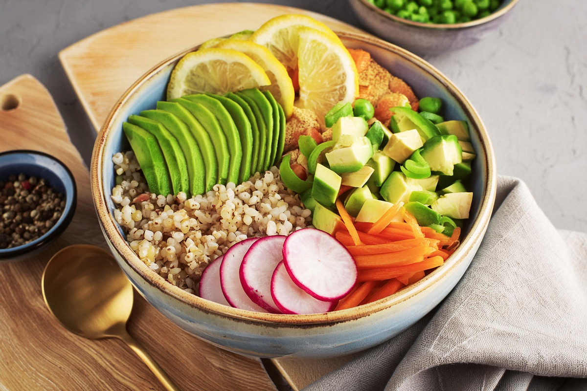 Vegane Bowl mit braunem Reis, Karotten, Radieschen, Tofu, Zitrone, Gurken, Soja Sauce