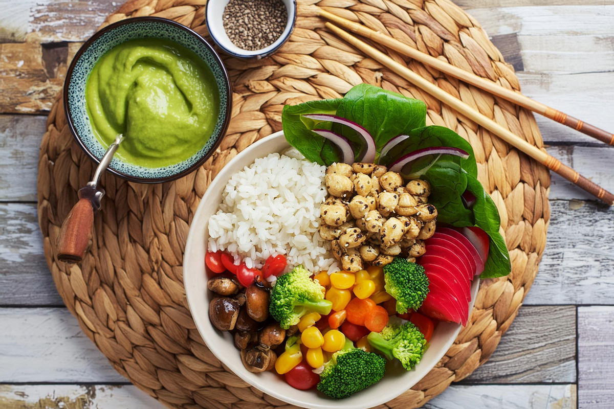 Vegane Bowl mit Kichererbsen, Mais, Paprika, Avocadodip, Karotten, Brokkoli, rote Beete