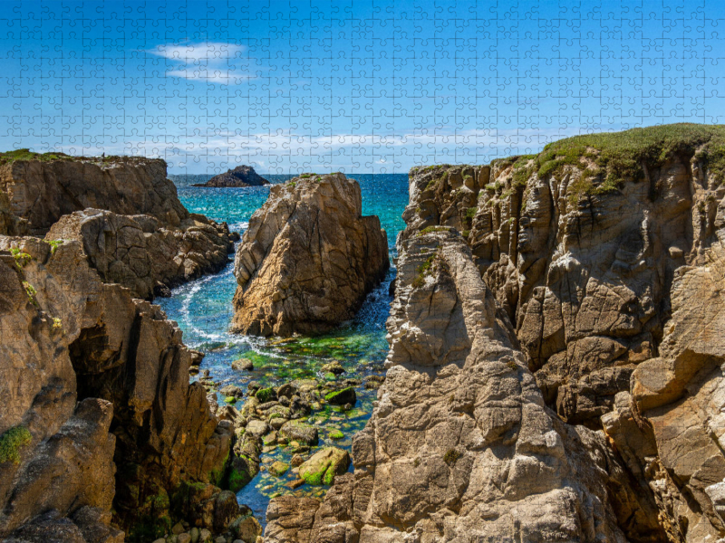 Blick an der Felsküste auf ein blau und grün schimmerndes Wasser