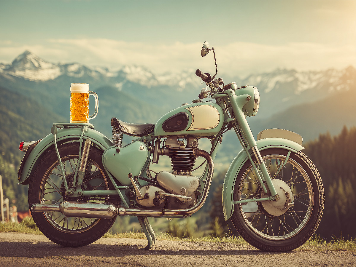 Oldtimer-Motorrad mit Bierkrug vor Alpenpanorama
