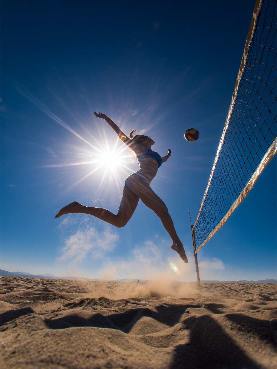 Sexy Volleyballspielerin springt im Sand unter der Sonne