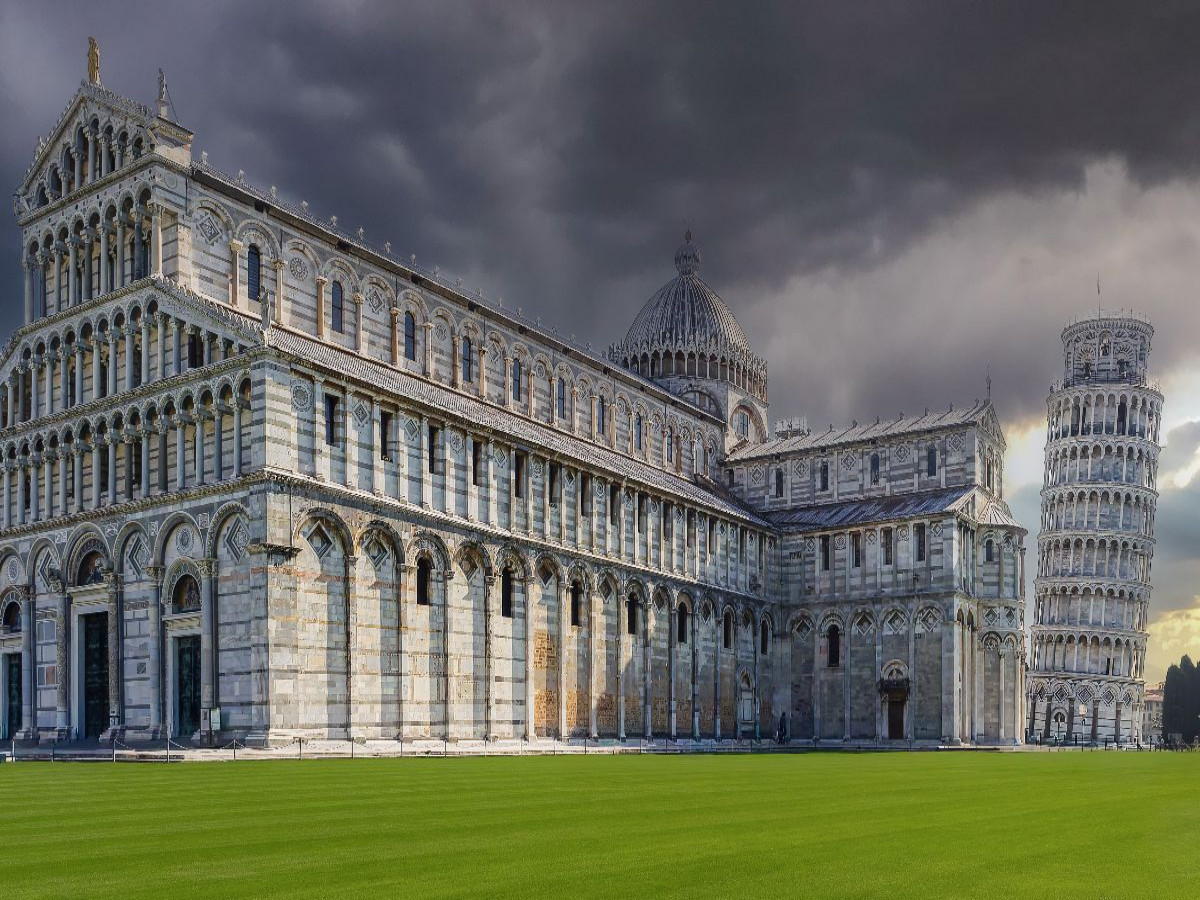 Pisa: Der monumentale Dom Santa Maria Assunta und der weltberühmte Schiefe Turm auf dem leuchtend grünen Rasen der Piazza dei Miracoli.