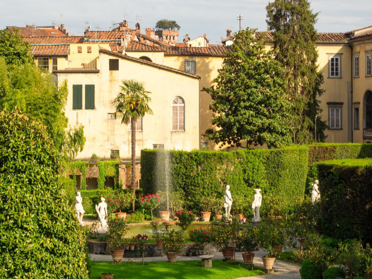 Lucca: Der prachtvolle barocke Garten des Palazzo Pfanner mit antiken Statuen, mediterranen Zitrusbäumen und einer plätschernden Fontäne im Frühlingslicht.