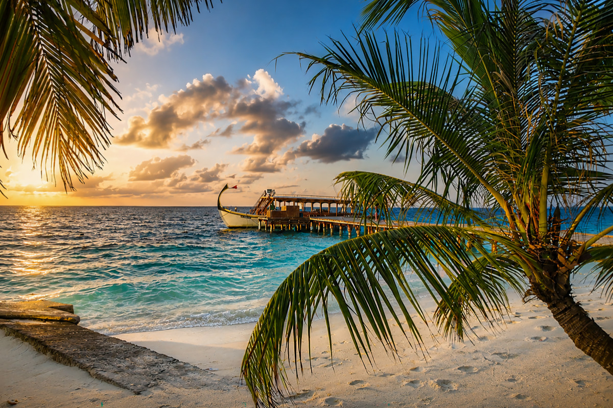 Sonnenuntergang am Malediven-Strand mit traditionellem Dhoni-Boot und Palmen