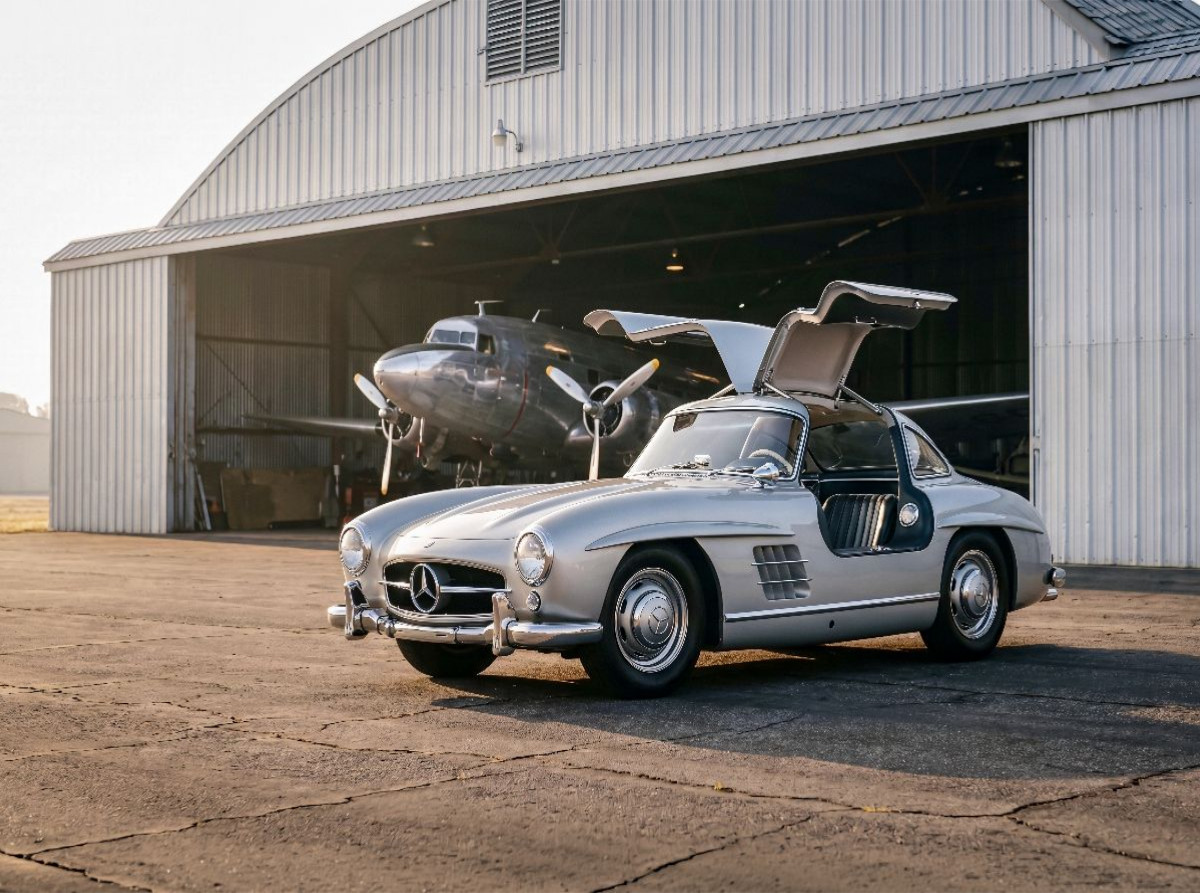 Mercedes-Benz 300 SL „Flügeltürer“ (Deutschland, 1954-57) vor einem Flugzeughangar im Morgenlicht